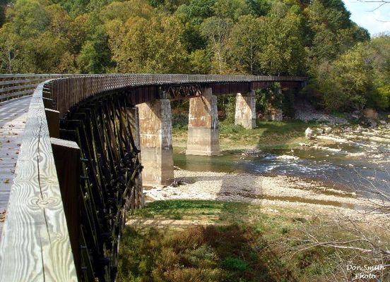 Alvarado - Railroad Trestle
A RAILROAD FROM ABINGDON, VA. LINKING SEVERAL SMALL TOWNS AND COMMUNITIES WAS STARTED IN THE 1880s.  BY 1918 IT RAN FROM ABINGDON TO ELKLAND, N. C. WHICH IS NOW CALLED TODD.  DAMASCUS, TAYLOR'S VALLEY, GREEN COVE AND WHITE TOP WERE AMONG THE STOPS ON IT'S ROUTE.  THERE WERE 100 TRESTLES AND BRIDGES ON THE RAIL LINE.
 
THE VIRGINIA CREEPER WAS STEAM POWERED AND HAULED FREIGHT AND PASSENGERS.  THE STEAM ENGINE WAS REPLACED BY N&W IN 1956 WITH A DIESEL LOCOMOTIVE.   IT CONTINUED IN OPERATION UNTIL MARCH 31, 1977 WHEN THE LAST TRAIN RAN.  THE ROADBED HAS BEEN CONVERTED TO A VERY POPULAR HIKING-BIKING TRAIL.  PICTURED IS THE TRESTLE AT THE HEADWATERS OF SOUTH HOLSTON LAKE WHERE THE MIDDLE AND SOUTH FORKS OFTHE HOLSTON RIVER MEET.  Courtesy of Don Smith [email]dsmith1043@comcast.net[/email]
 

